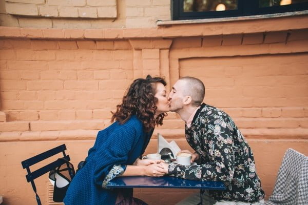 Casal se beijando por cima de uma mesa de café