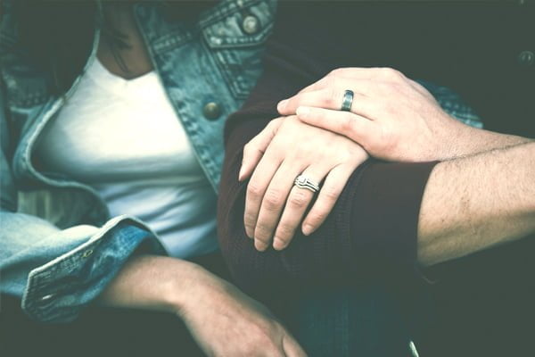 Foto das mãos de um casal mostrando as alianças