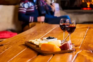 Casal com taças de vinho e queijos sobre a mesa