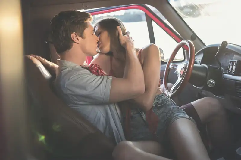 Casal apaixonado se beijando dentro do carro