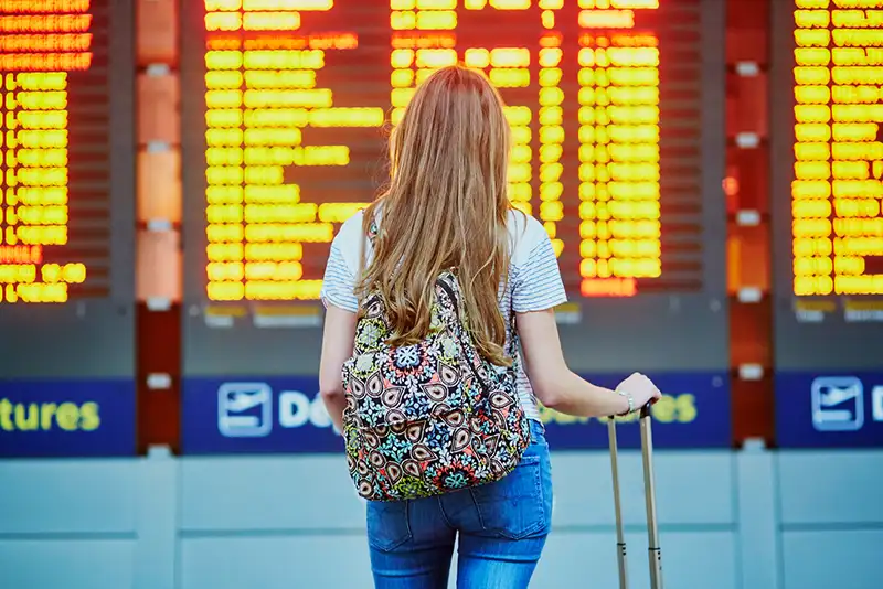 Mulher no aeroporto olhando a relação de viagens