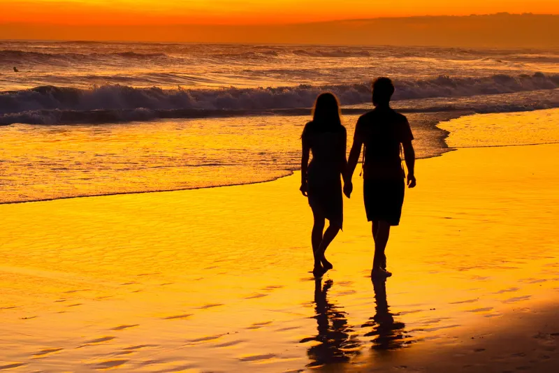 Silhueta de casal passeando na praia - Como beijar pela primeira vez alguém