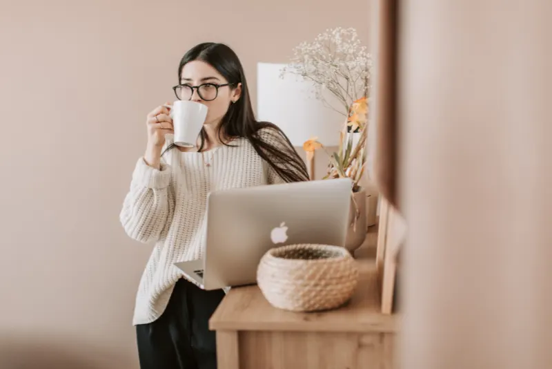 Mulher de óculos mexendo no computador e tomando café - Como Lidar com Brigas no Relacionamento