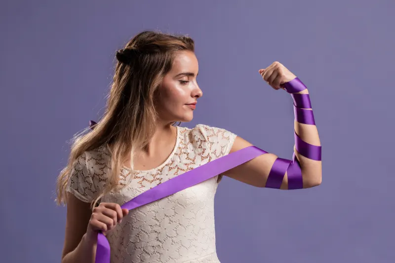 Mulher empoderada fazendo força com o braço envolto em uma faixa roxa - Como superar o término de um relacionamento
