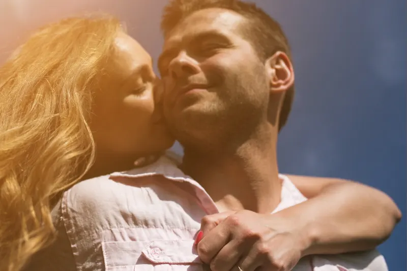 Mulher abrançando namorado por trás e beijando sua bochecha