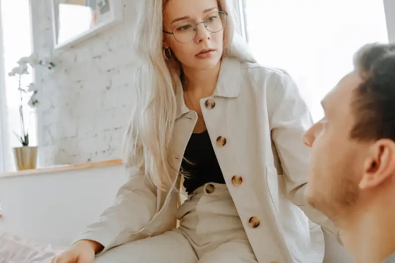 Mulher loira de óculos conversando com um homem