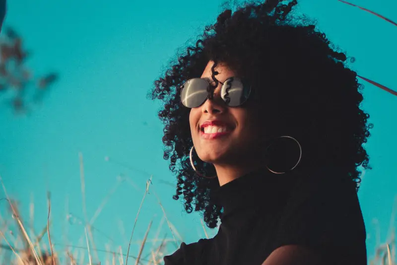 Mulher negra de óculos tirando foto e sorrindo