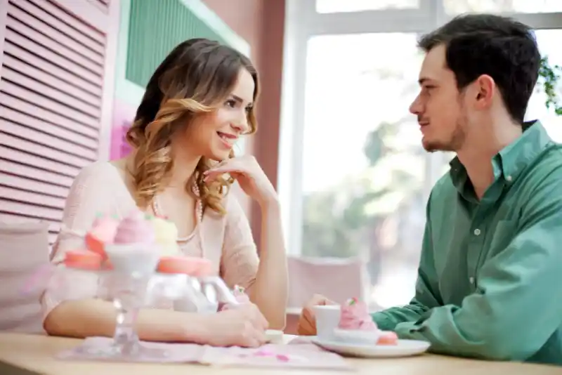 Casal conversando enquanto tomam um café ao ar livre