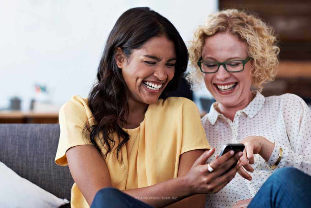 Amigas rindo de algo que viram no celular