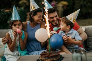 Familha comemorando o aniversário do filho pequeno com chapéu de aniversário e bexigas