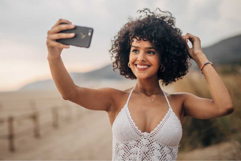 Linda mulher morena de cabelos cacheados tirando uma selfie ao ar livre