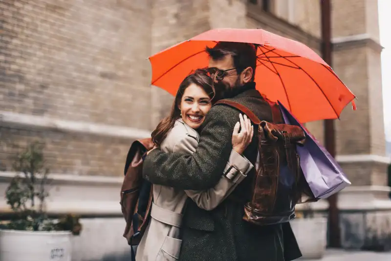 Casal compartilhando o mesmo guarda chuva - Foto de casal