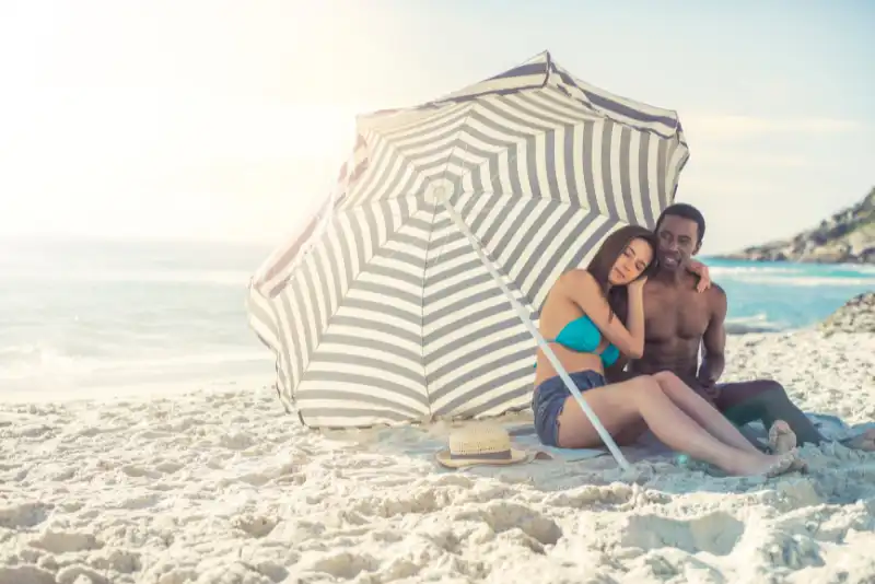 Casal compartilhando um guarda sol na praia