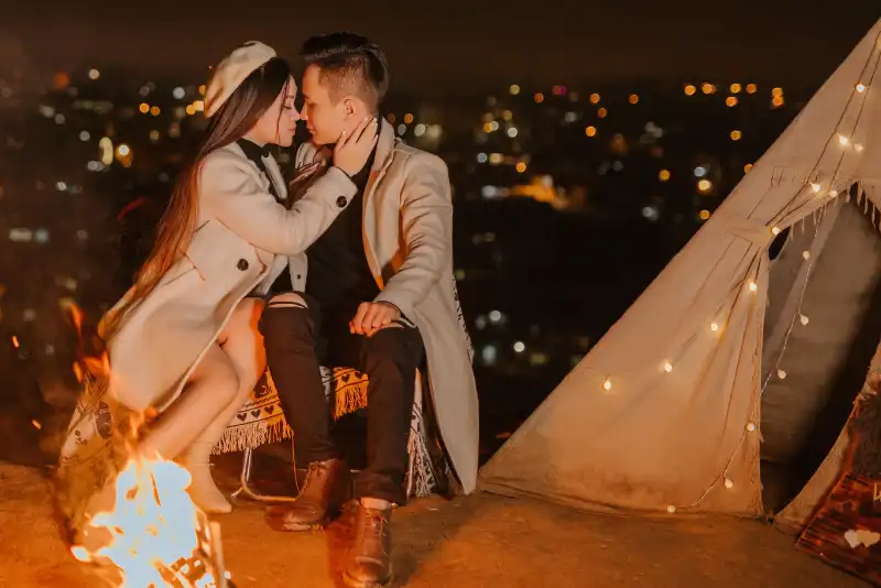 Casal sentando em frente a uma fogueira de noite