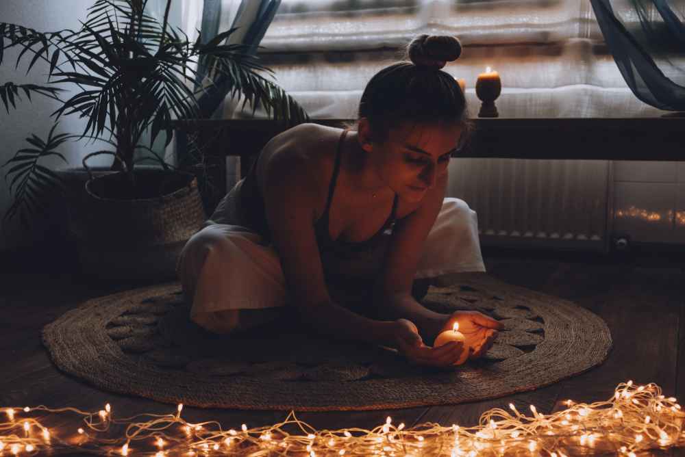 Mulher sentada no chão observando uma vela acesa - Amor próprio