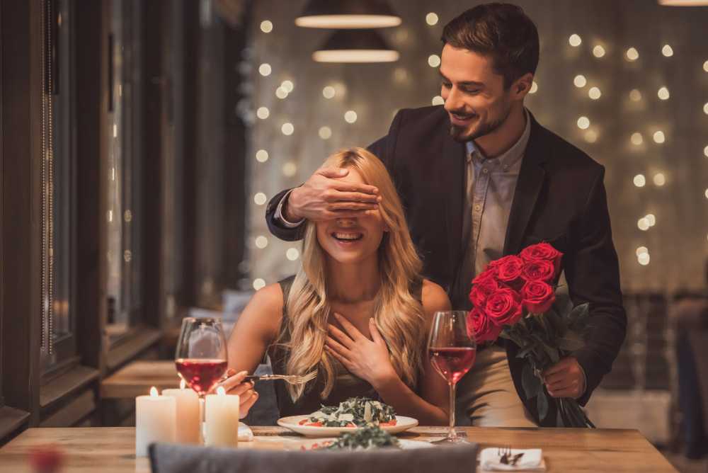 Coisas românticas para fazer com seu amor: Homem cobrindo os olhos de sua namorada ao fazer surpresa para ela com flores românticas