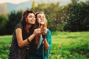 Duas amigas assoprando uma flor