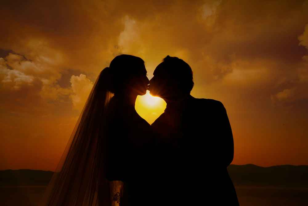 Silhueta de casal se beijando ao por do sol