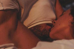 Mulher beijando e tirando camiseta de seu namorado