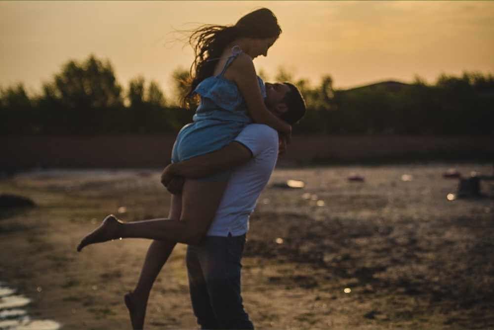 Homem carregando mulher no colo na praia
