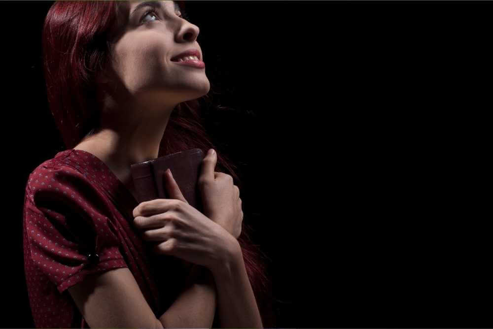 Mulher com bíblia na mão orando a Deus