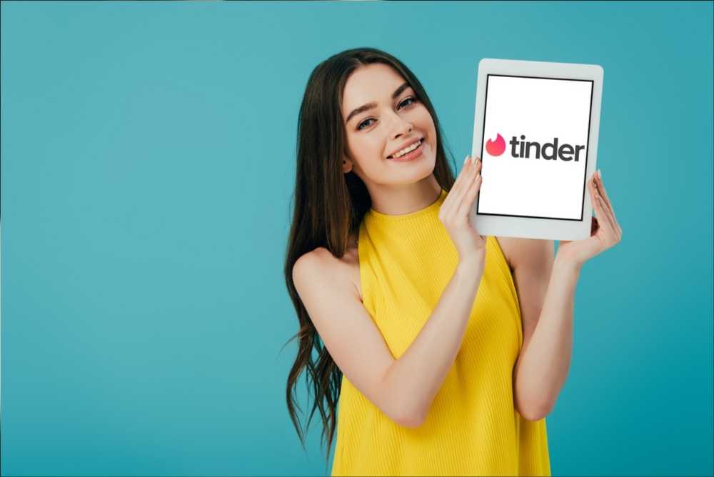 Mulher segurando tablet com o logo do Tinder - Aplicativos de relacionamento