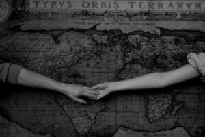Casal de mãos dadas com mapa mundi atrás