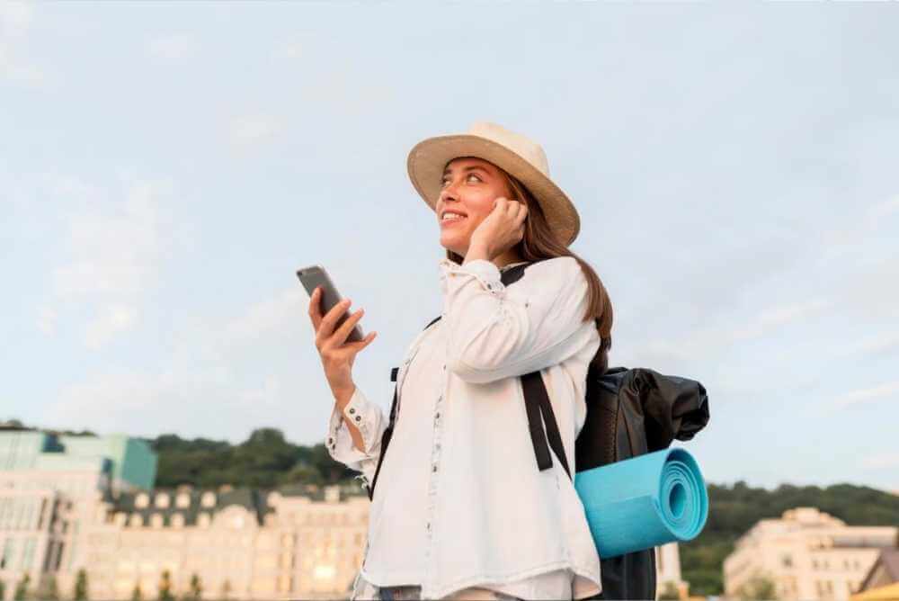 Mulher turista com celular na mão olhando para cima com aplicativos de viagem