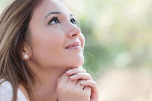 Mulher olhando para o alto com a mão no queixo agradecendo a Deus