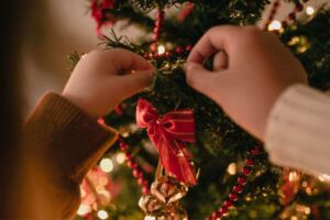 Criança arrumando um enfeite de natal na árvore de natal