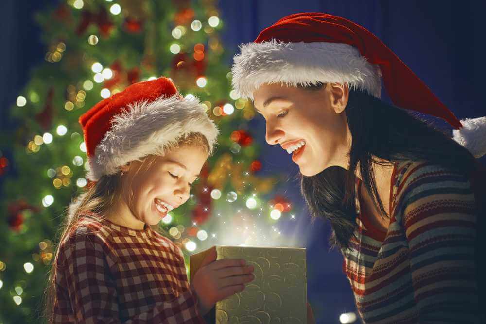 Mãe e filha de gorro de Natal abrindo caixa de presente de Natal