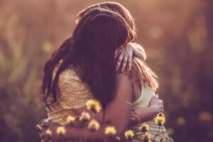 Duas amigas se abraçando em um campo com flores
