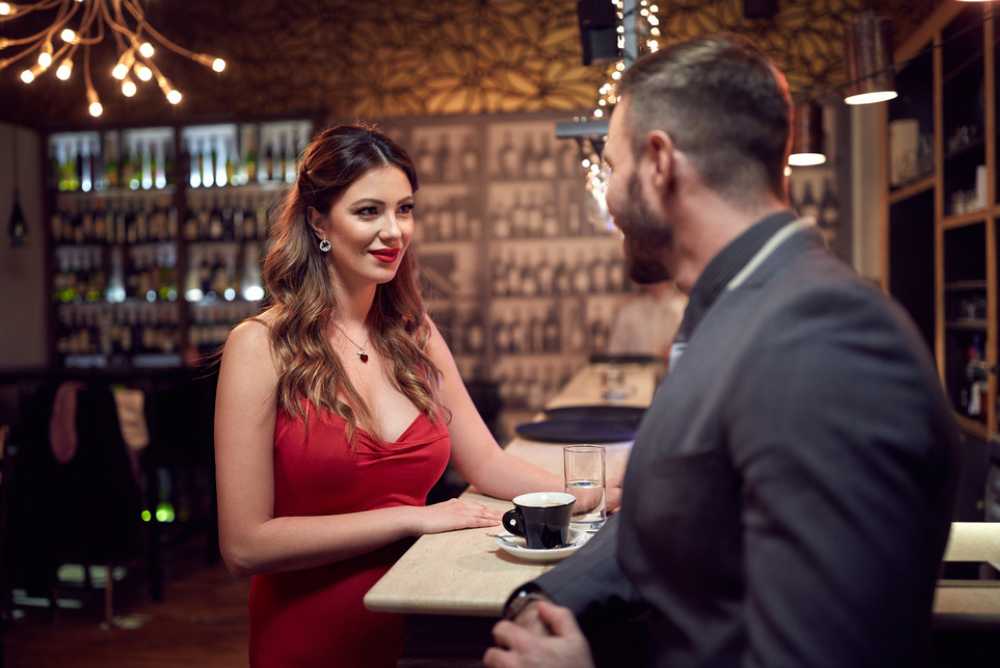 Mulher atraente de vestido vermelho flertando com homem em um café
