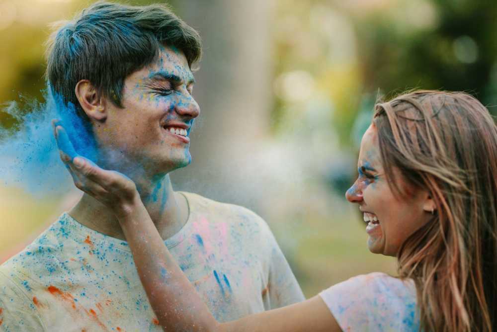 Mulher jogando tinta azul no rosto do seu namorado