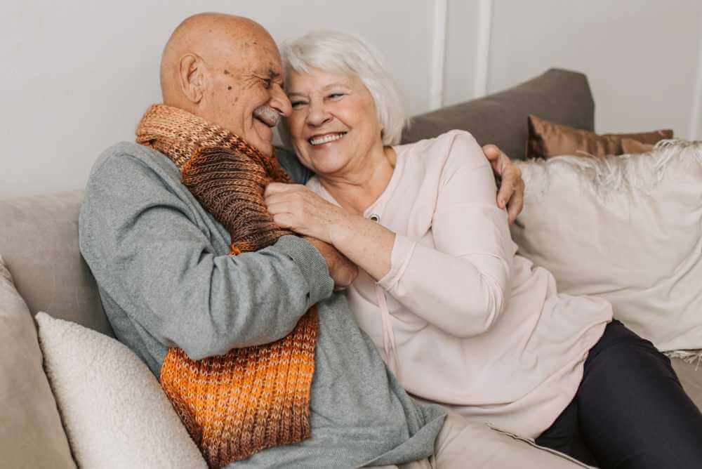 Feliz casal de idosos demonstrando carinho no sofá
