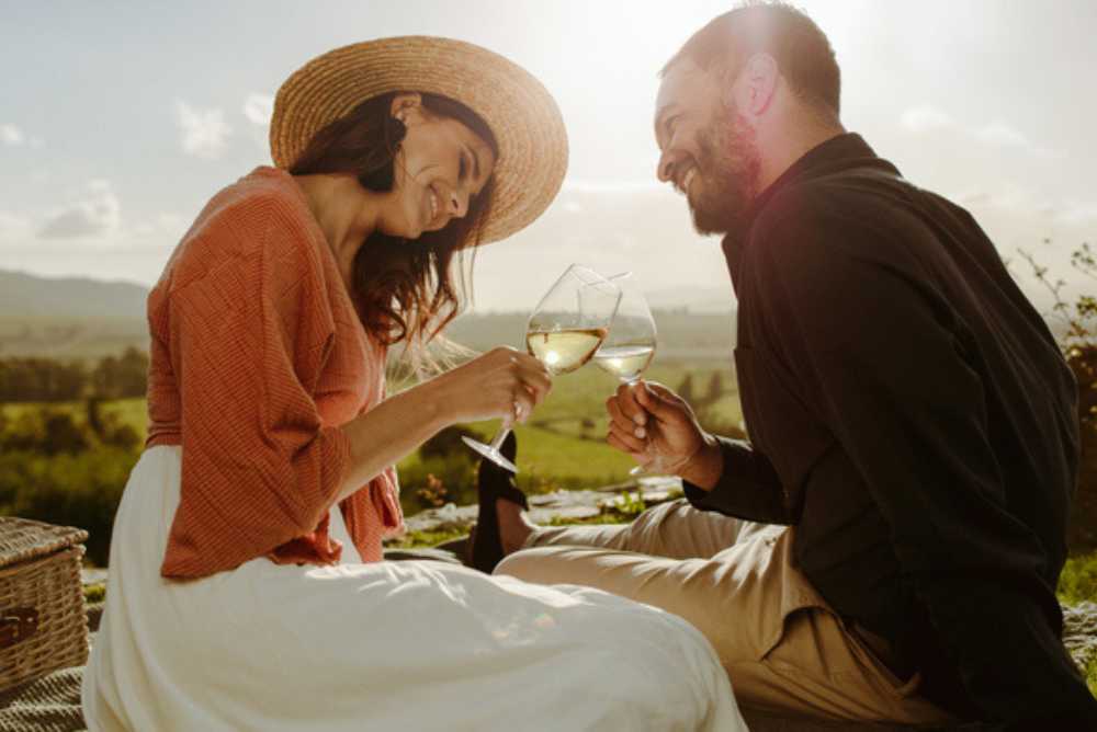 Casal apaixonado fazendo um piquenique e brindando uma taça de vinho branco
