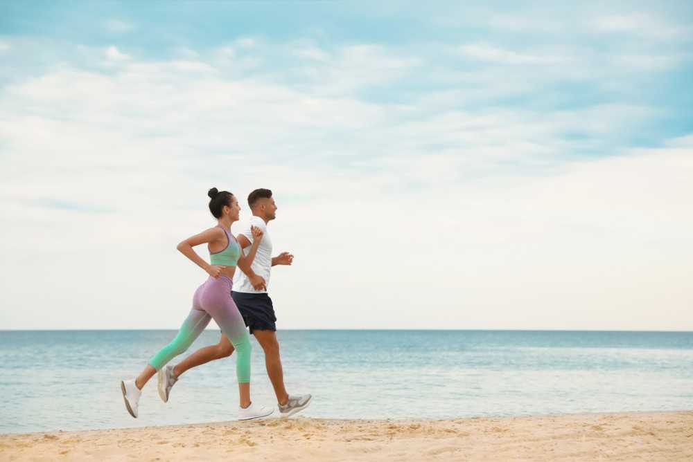 Casal correndo na areia da praia