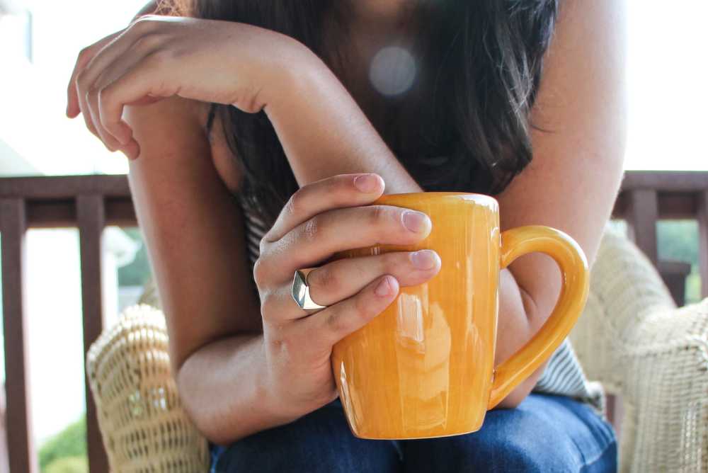 Mulher morena segurando uma caneca de café laranja