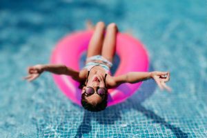 Menina em uma boia rosa na piscina