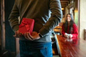 Homem fazendo surpresa com presente para sua parceira