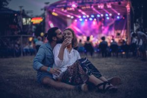 Casal apaixonado sentado na grama em um show ao ar livre