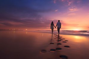 Casal romântico deixando pegadas na praia ao anoitecer